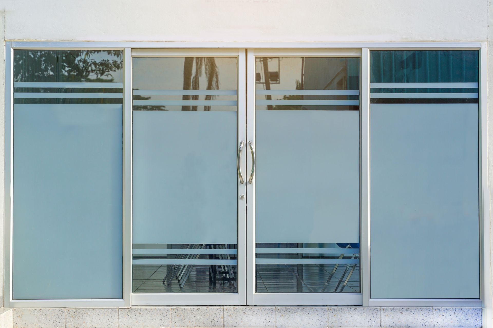 Glass sliding doors with frosted panes, set in a white wall with frosted stripe details.