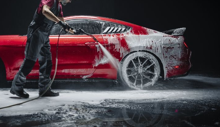 Green Jeep Gladiator truck, lifted with bronze rims, in a garage.
