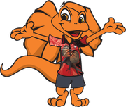 Orange cartoon lizard writing on paper; wearing shirt, shorts, and shoes.