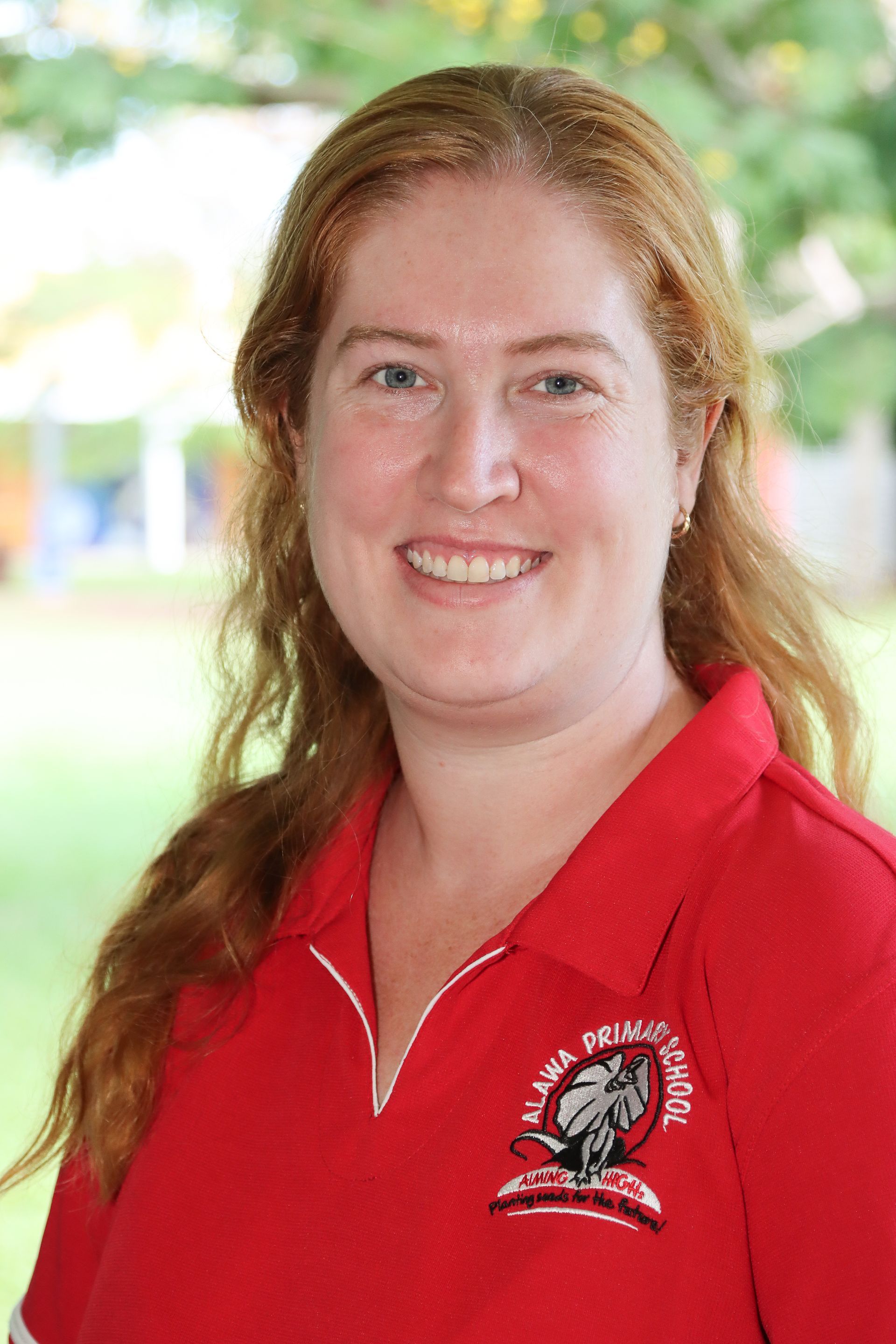 Two smiling girls with a cardboard model of a playground. Classroom setting, one in red hijab.