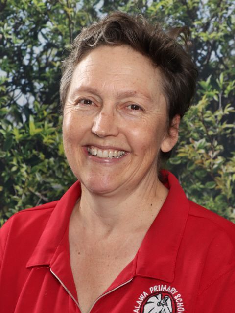 Woman with short brown hair, smiling. Wearing a red polo shirt with 