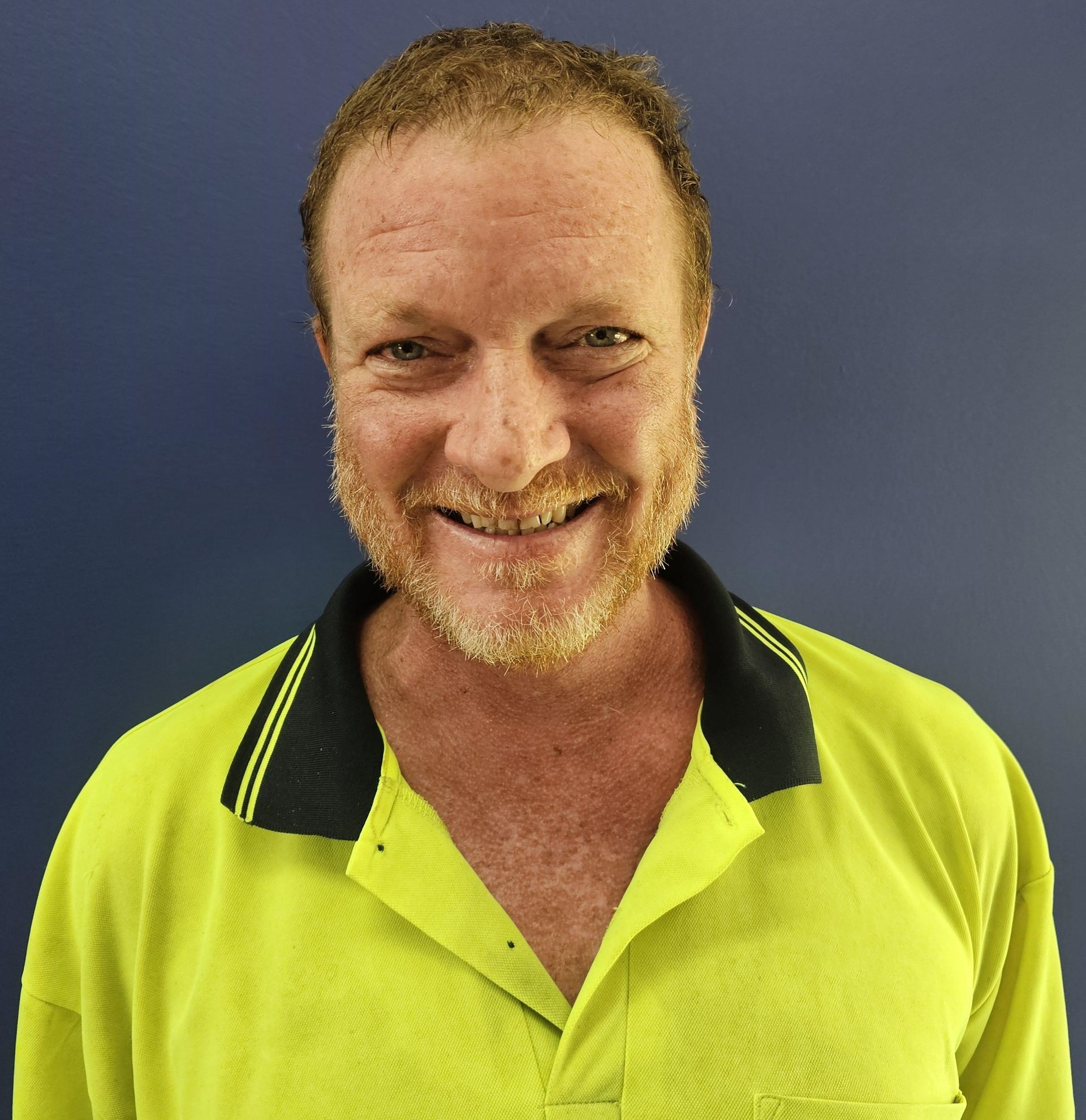 Woman in a red polo shirt smiling, with the logo of Akora Primary School.