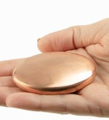 Hand holding a smooth, copper-colored, oval stone.