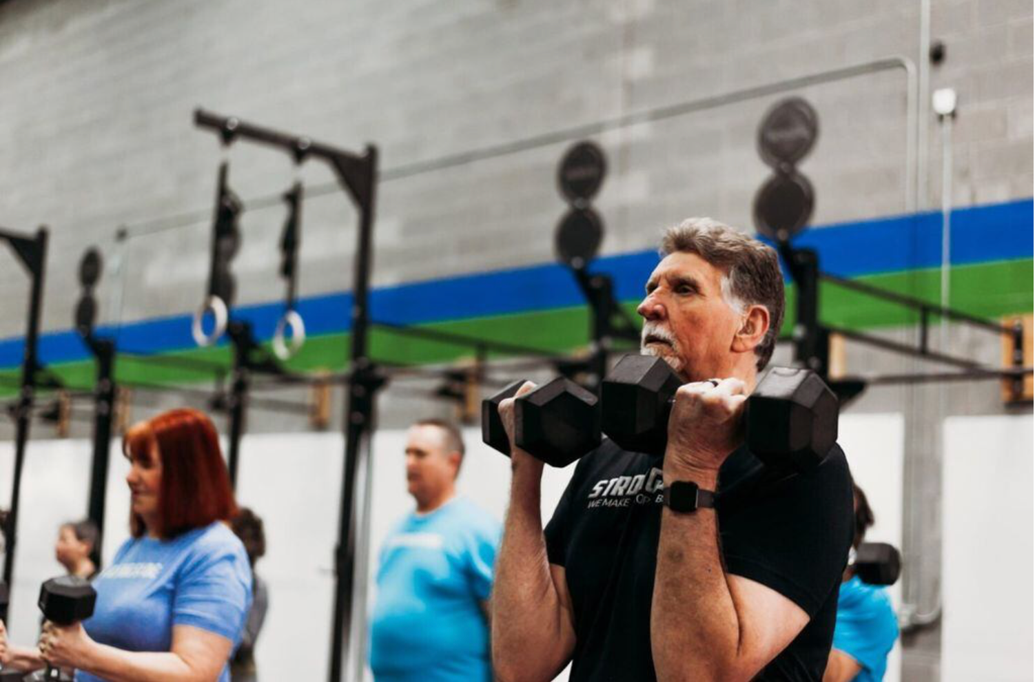A man is lifting a dumbbell in a gym.