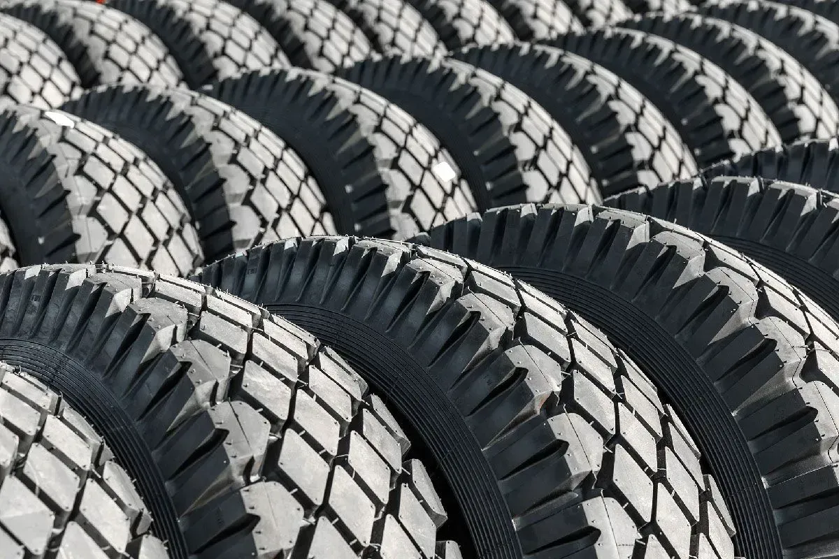 Row of new black tires with textured tread, outdoors.