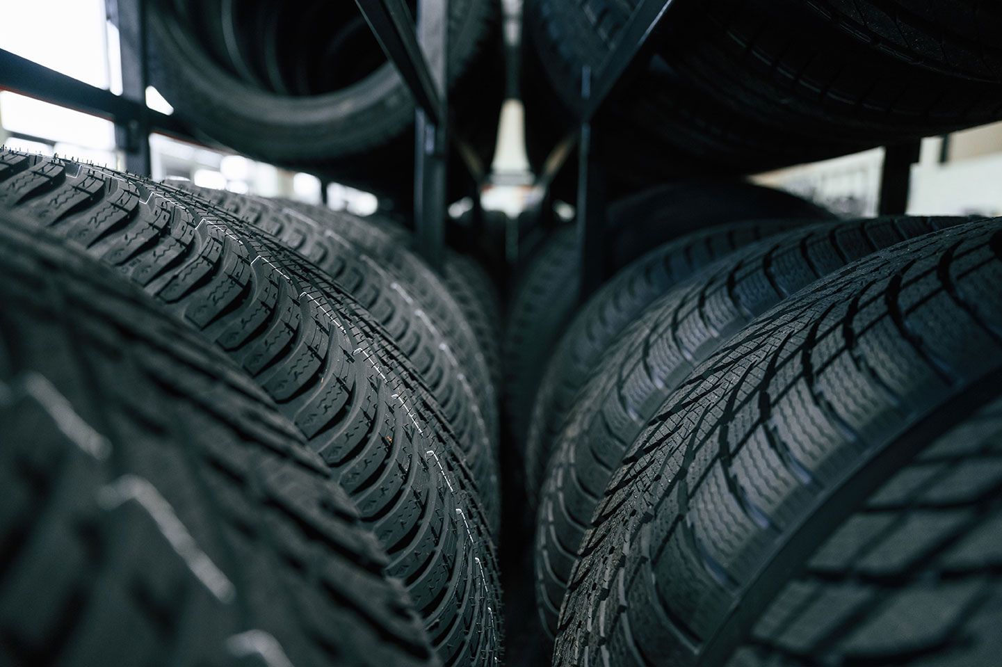 Tires neatly stacked on shelves in a shop, close-up view of tread pattern.