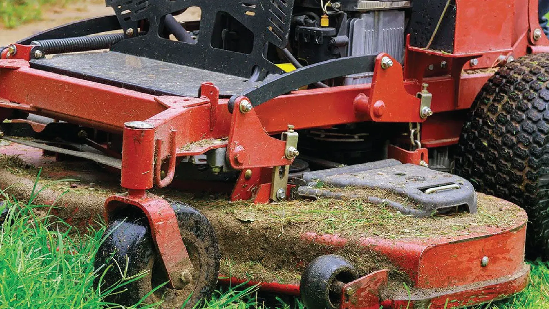 Red zero-turn mower cutting grass in a field.