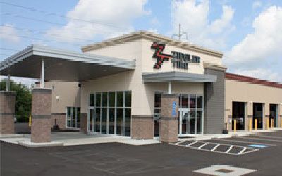 A Zinnser Tire shop with tan facade, glass windows, and a gray awning.