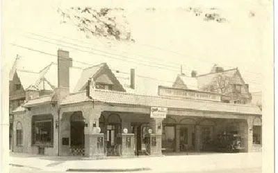 Vintage gas station with tiled roof and pumps under an overhang.
