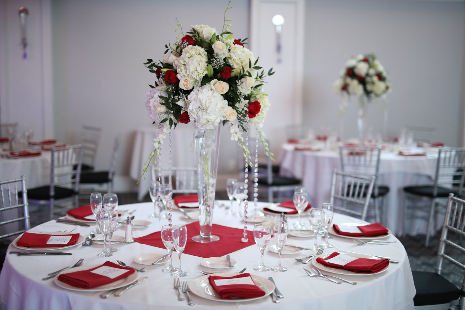 A table set for a wedding reception with a vase of flowers on it.