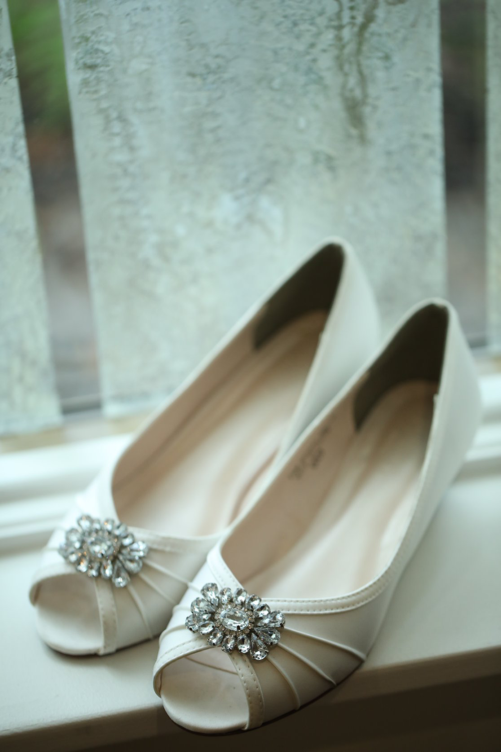 A pair of white shoes are sitting on a window sill.