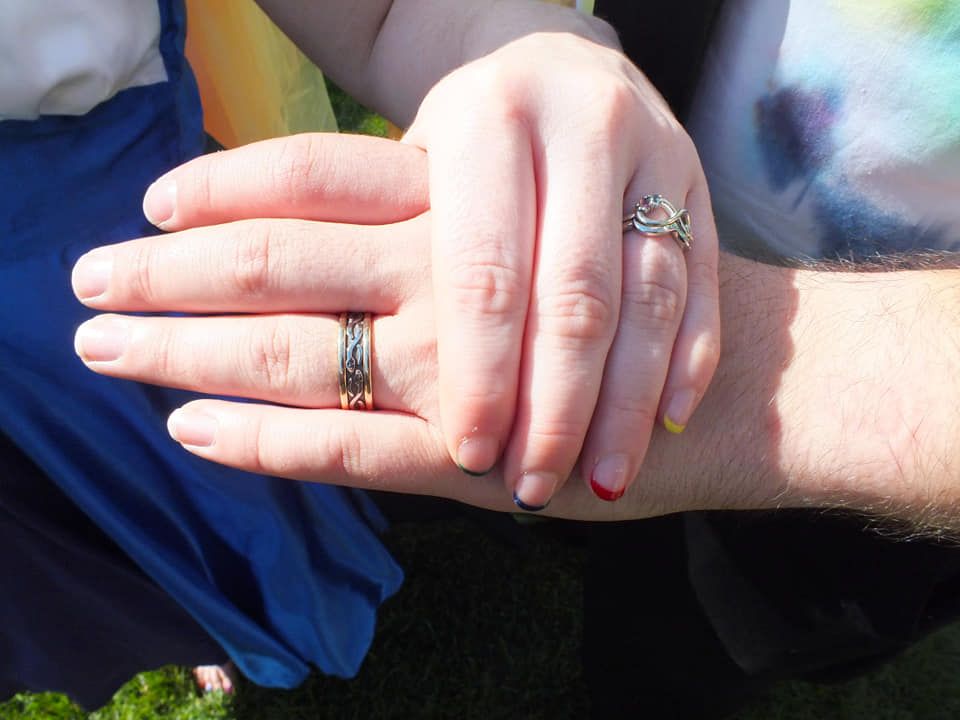 A man and a woman are holding hands with their wedding rings on their fingers.
