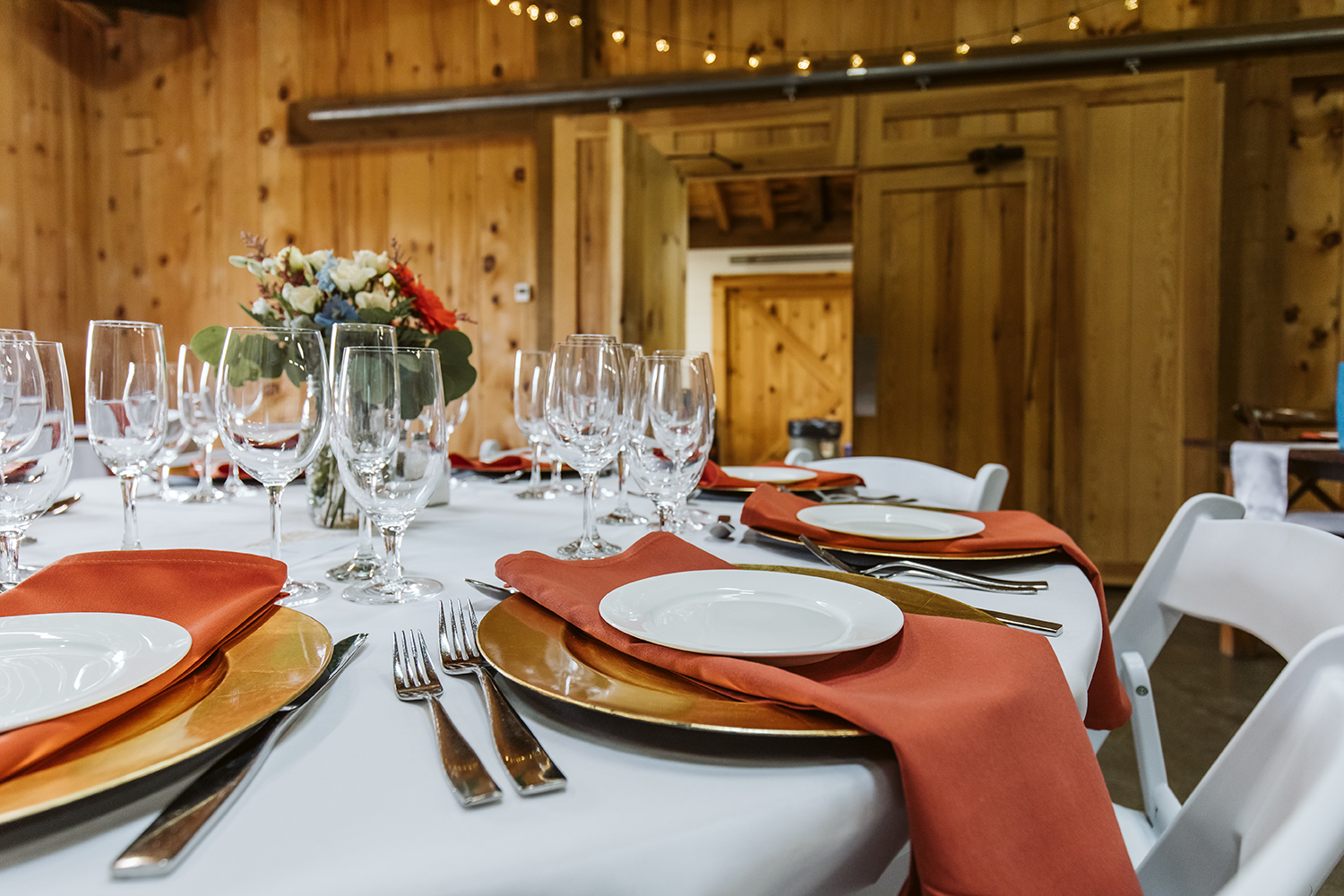 A table set for a wedding reception with plates , glasses , and napkins.