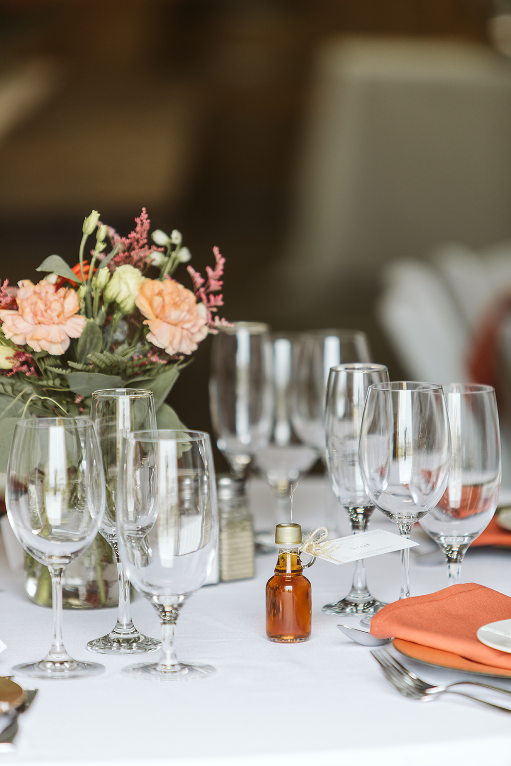 A table with a vase of flowers and wine glasses on it.