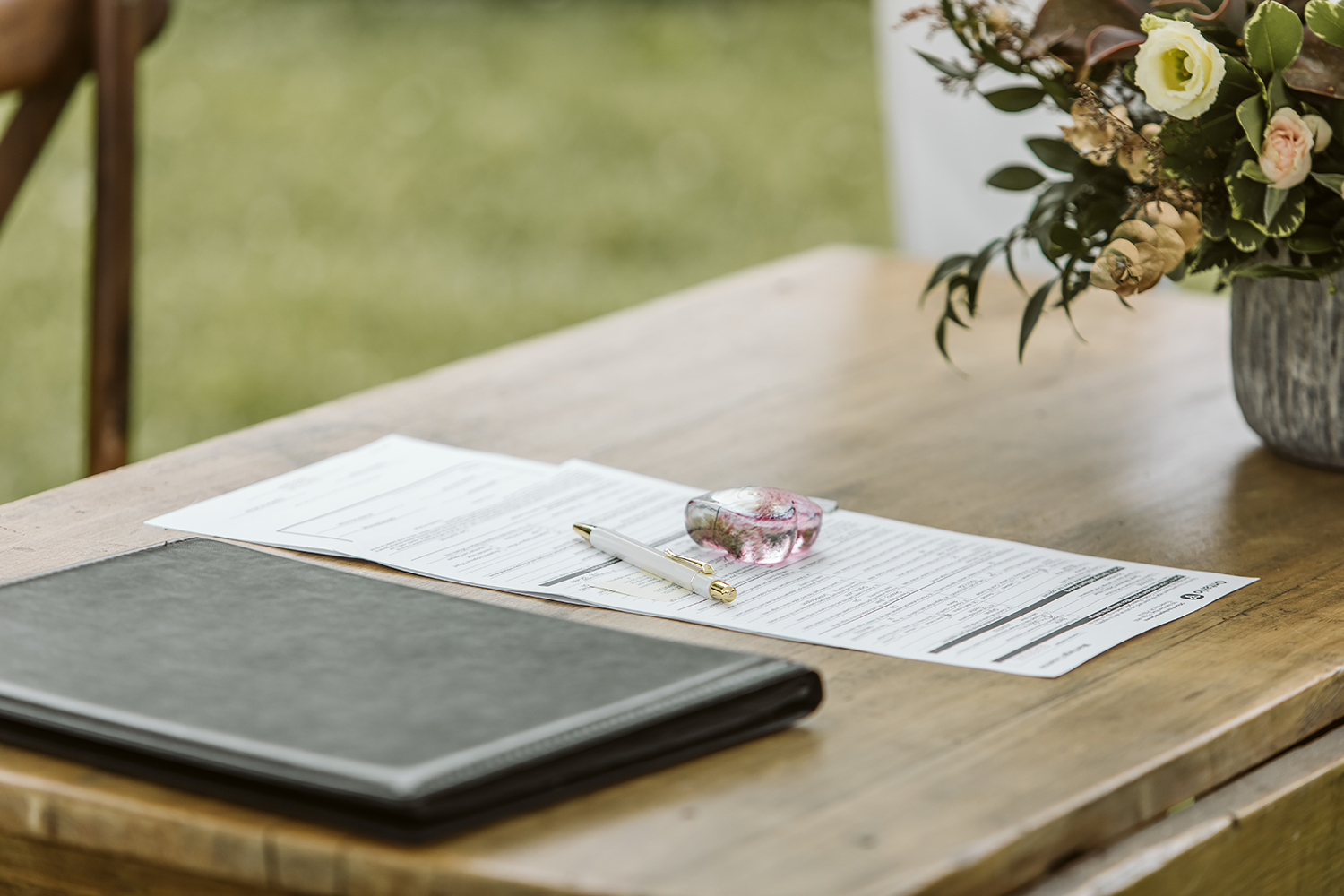 A wooden table with a book and a pen on it.