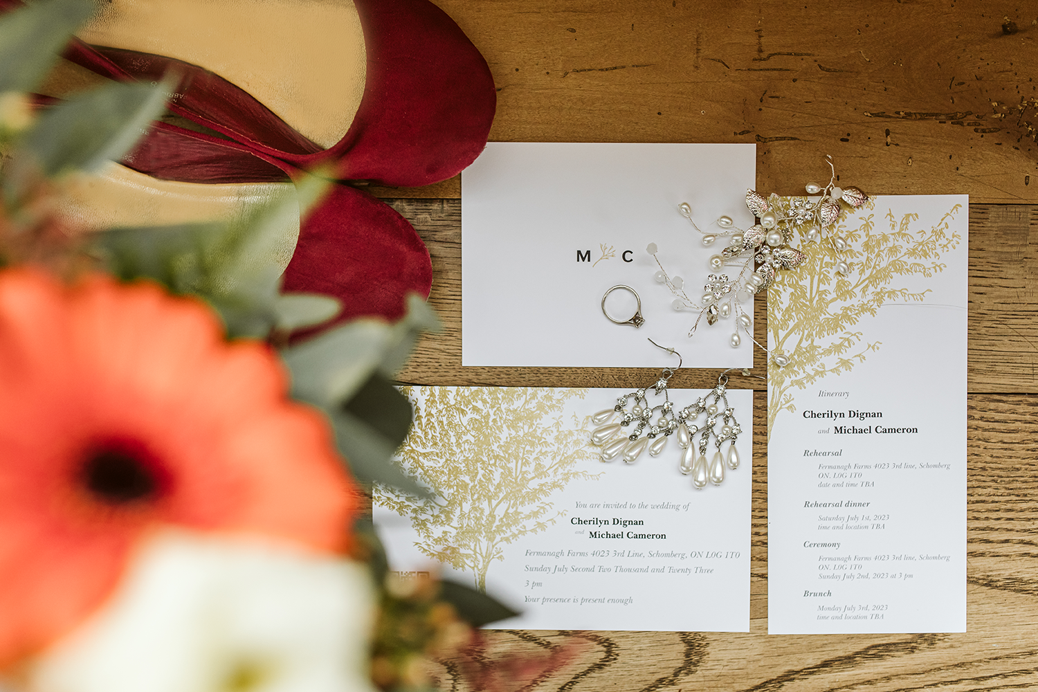 A wedding invitation is sitting on a wooden table next to a bouquet of flowers.