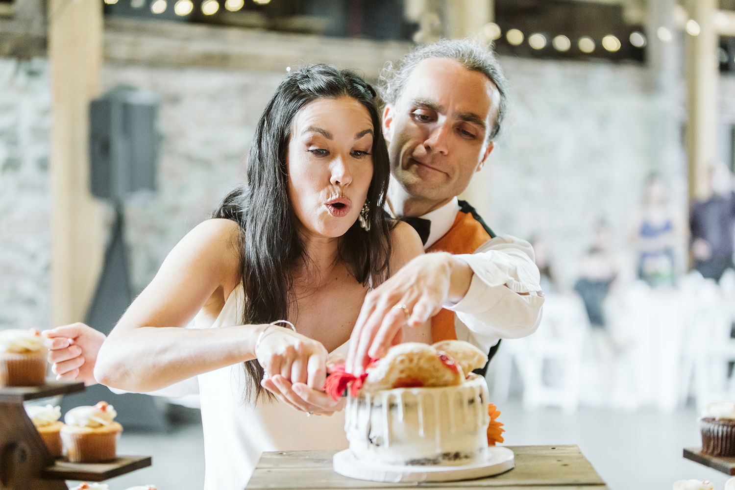 A bride and groom are cutting their wedding cake together.