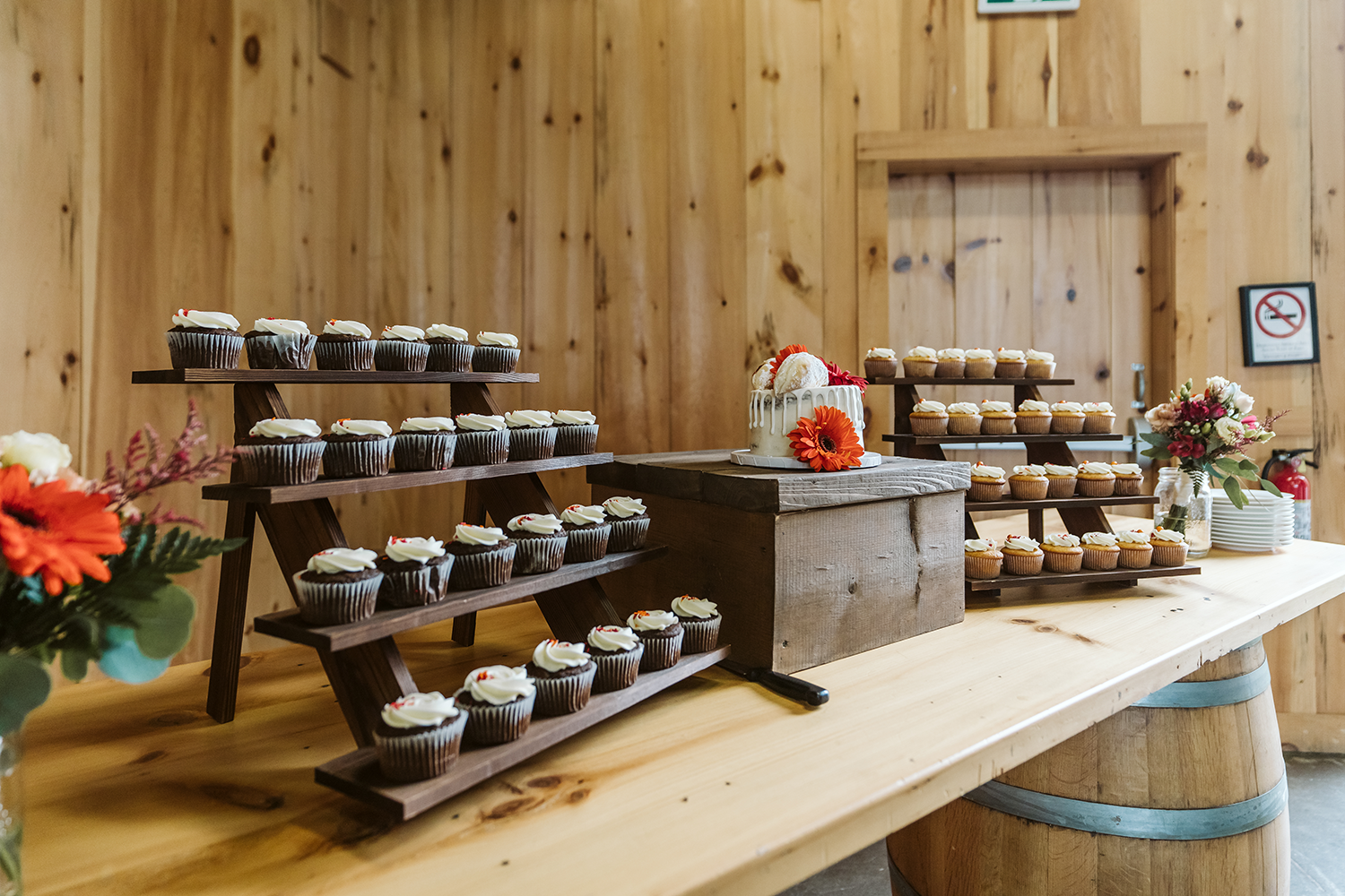 A wooden table topped with cupcakes and a cake.