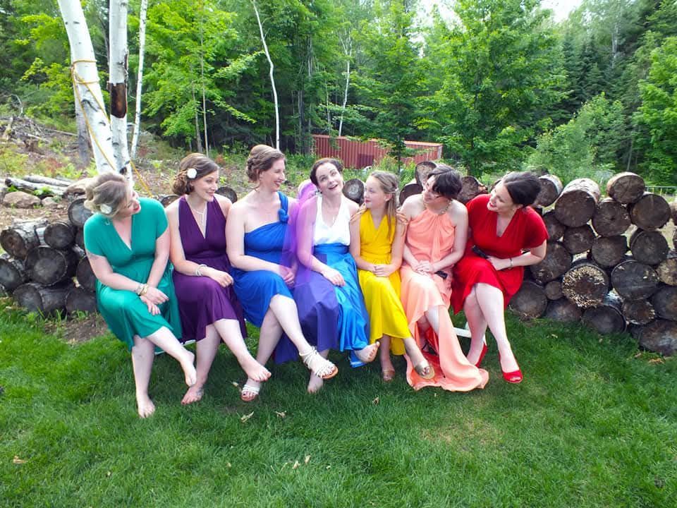 A group of women are sitting on a pile of logs.