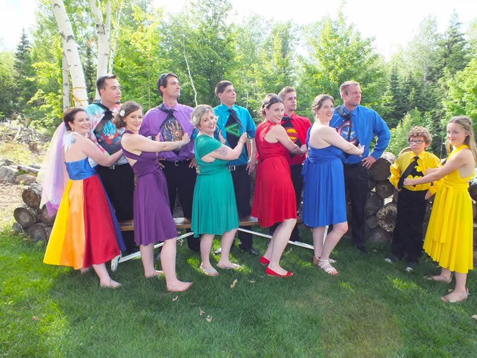 A group of people in rainbow colored dresses are posing for a picture.