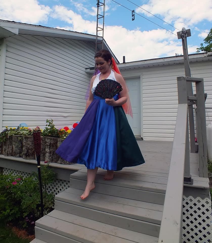 A woman in a colorful dress is walking down stairs holding a fan