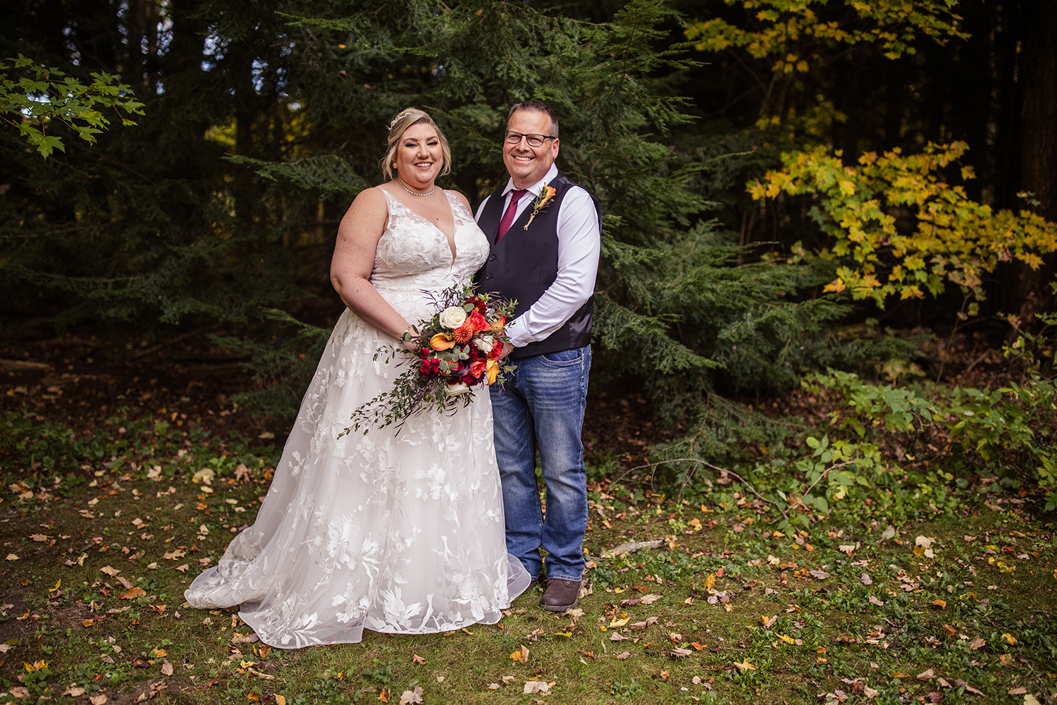 A bride and groom are posing for a picture in the woods.