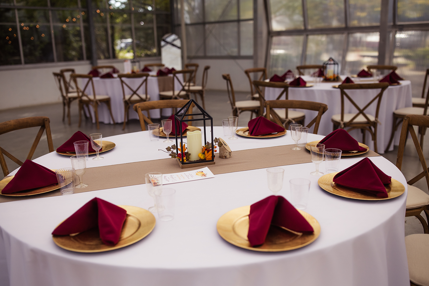 A table set for a wedding reception with red napkins and gold plates.