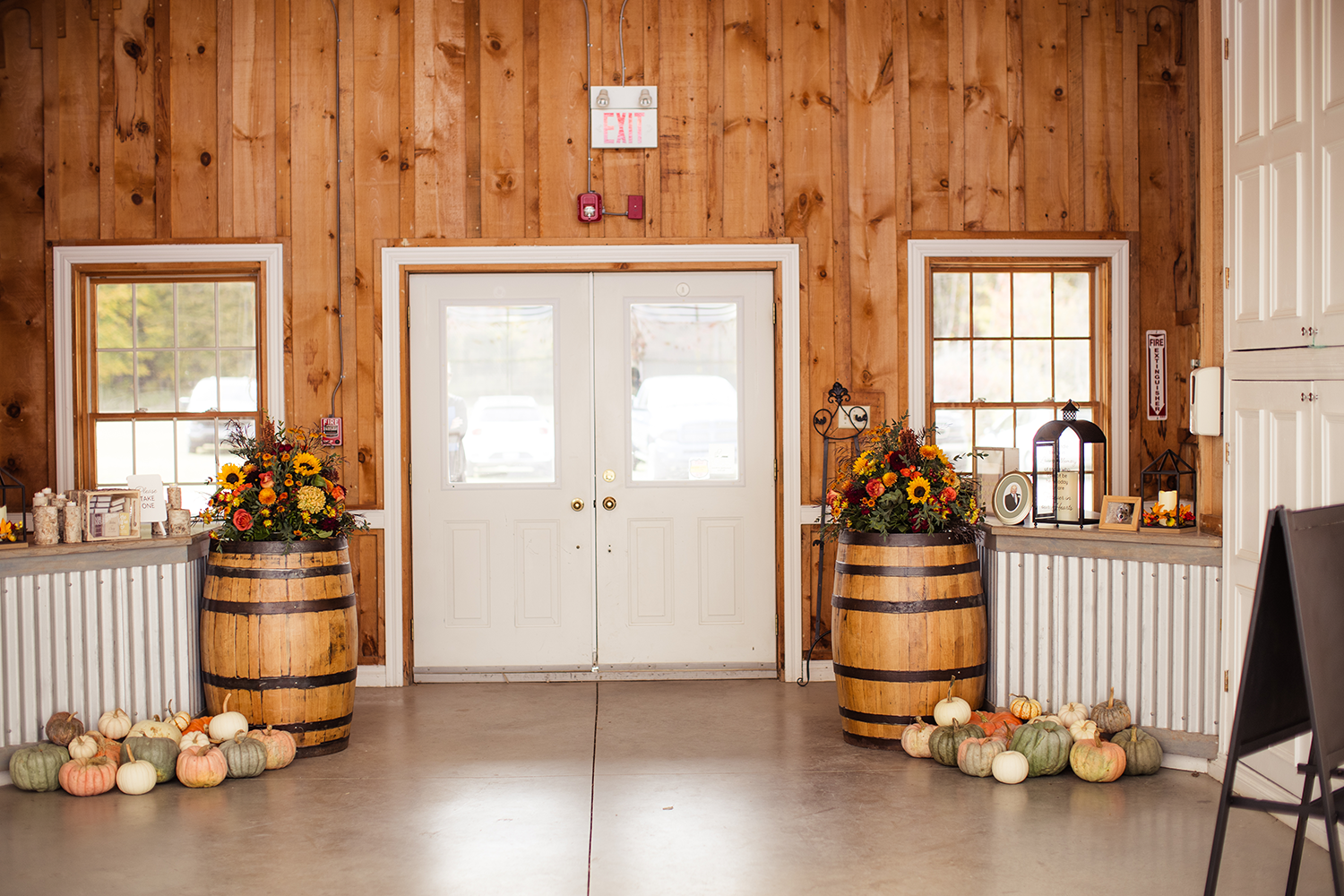 A room with wooden barrels filled with pumpkins and flowers.