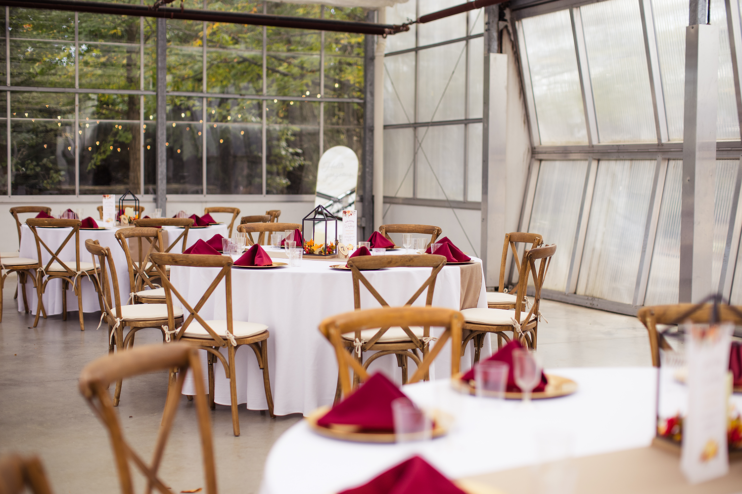 A greenhouse with tables and chairs set up for a wedding reception.