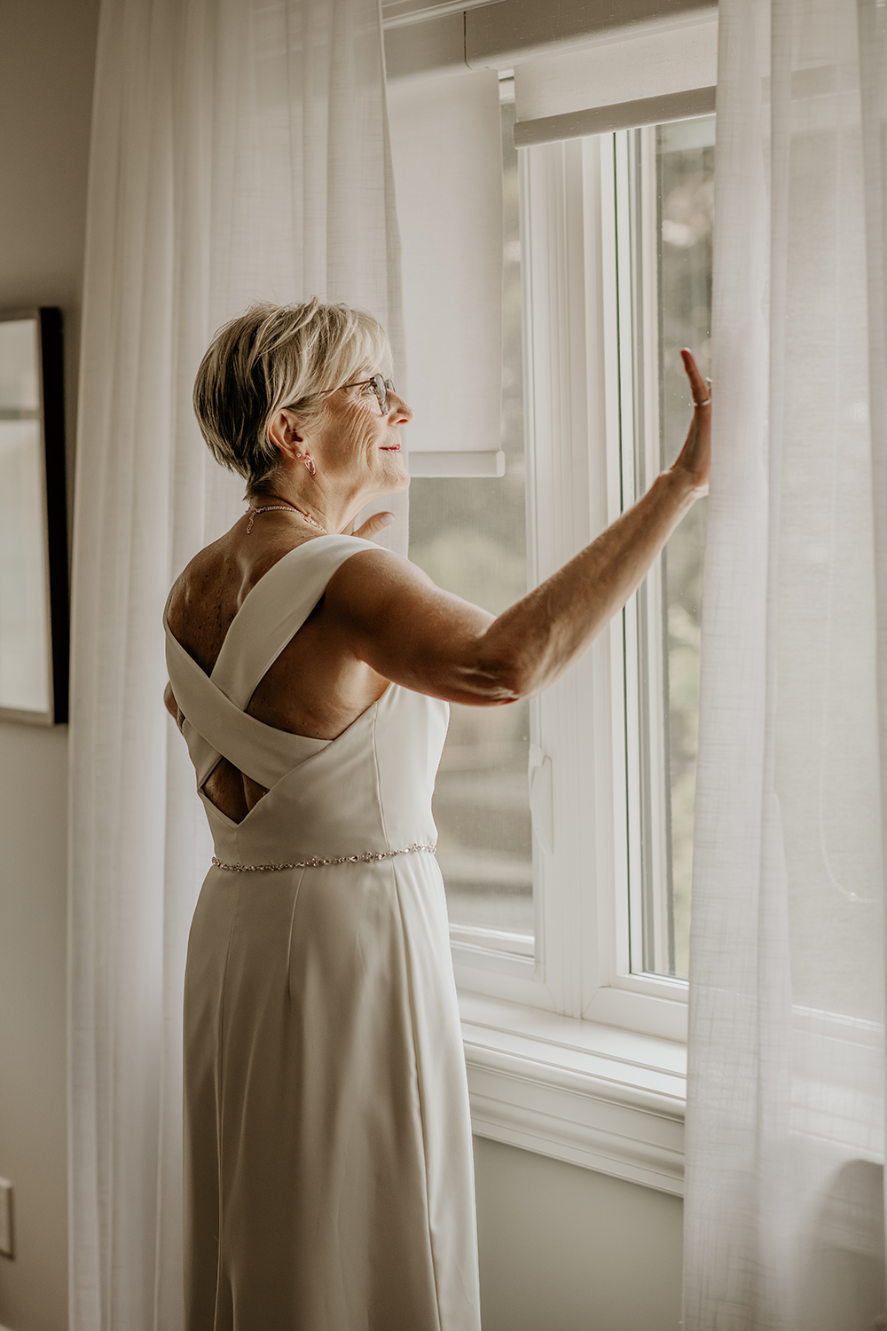 A woman in a wedding dress is looking out of a window.