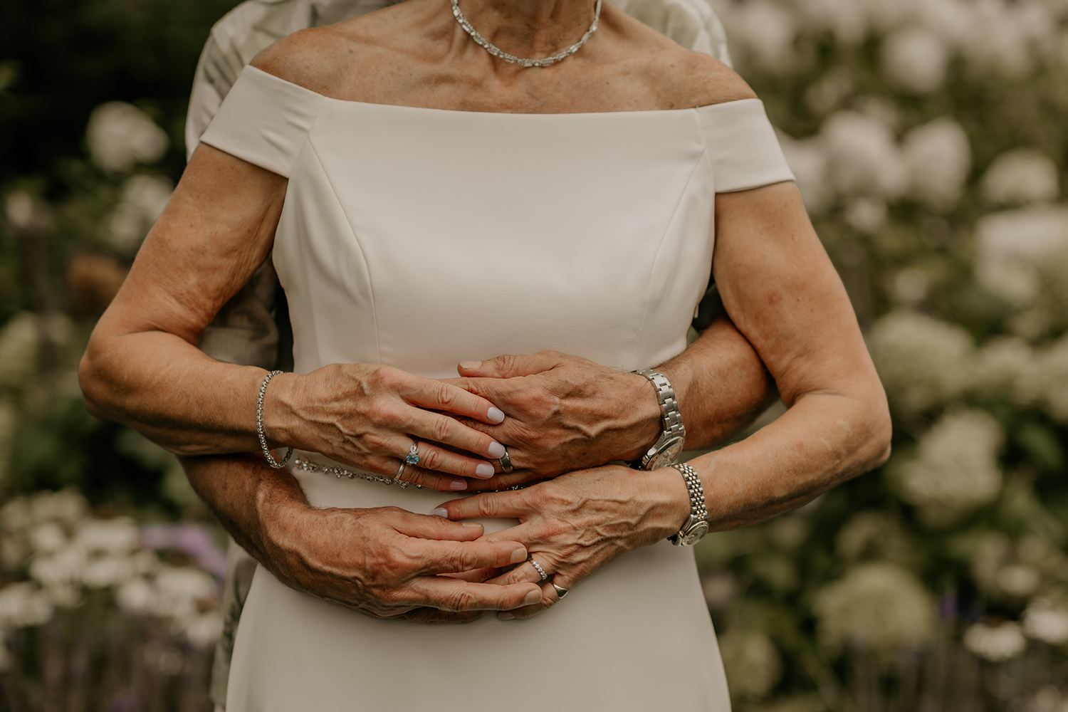 A man is hugging a woman in a white dress.