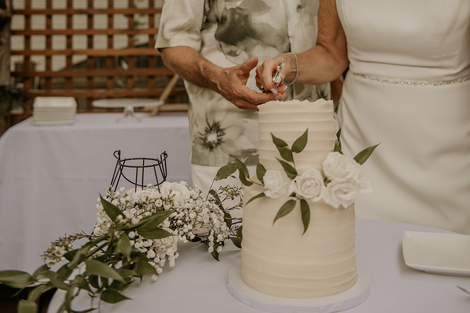 A bride and groom are cutting their wedding cake on a table.