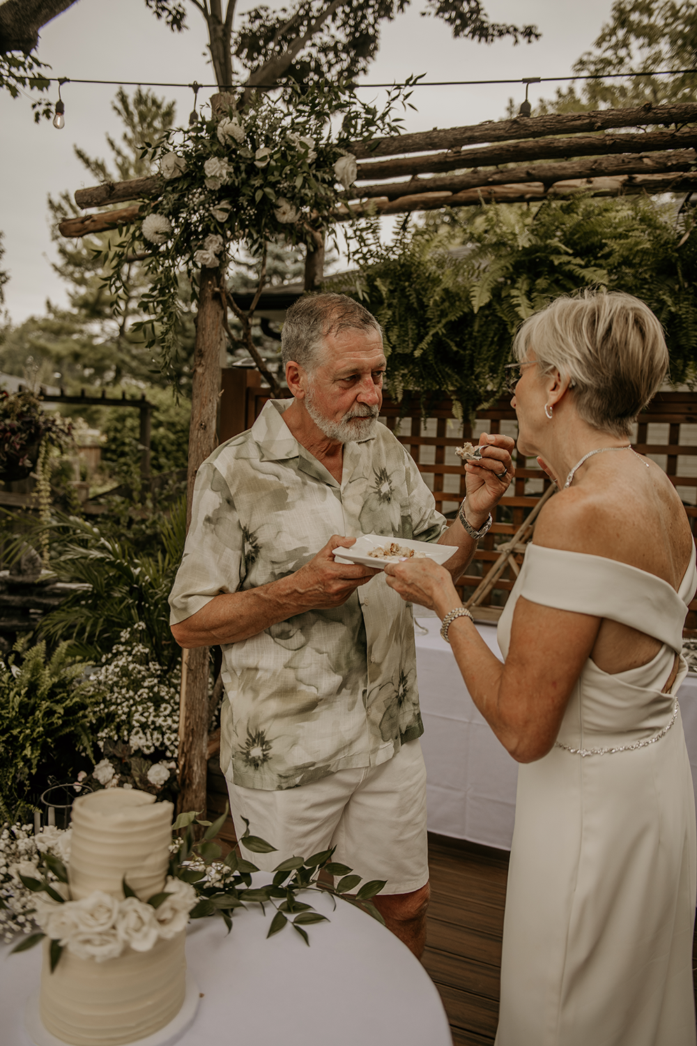 A bride and groom are eating a piece of cake at their wedding reception.