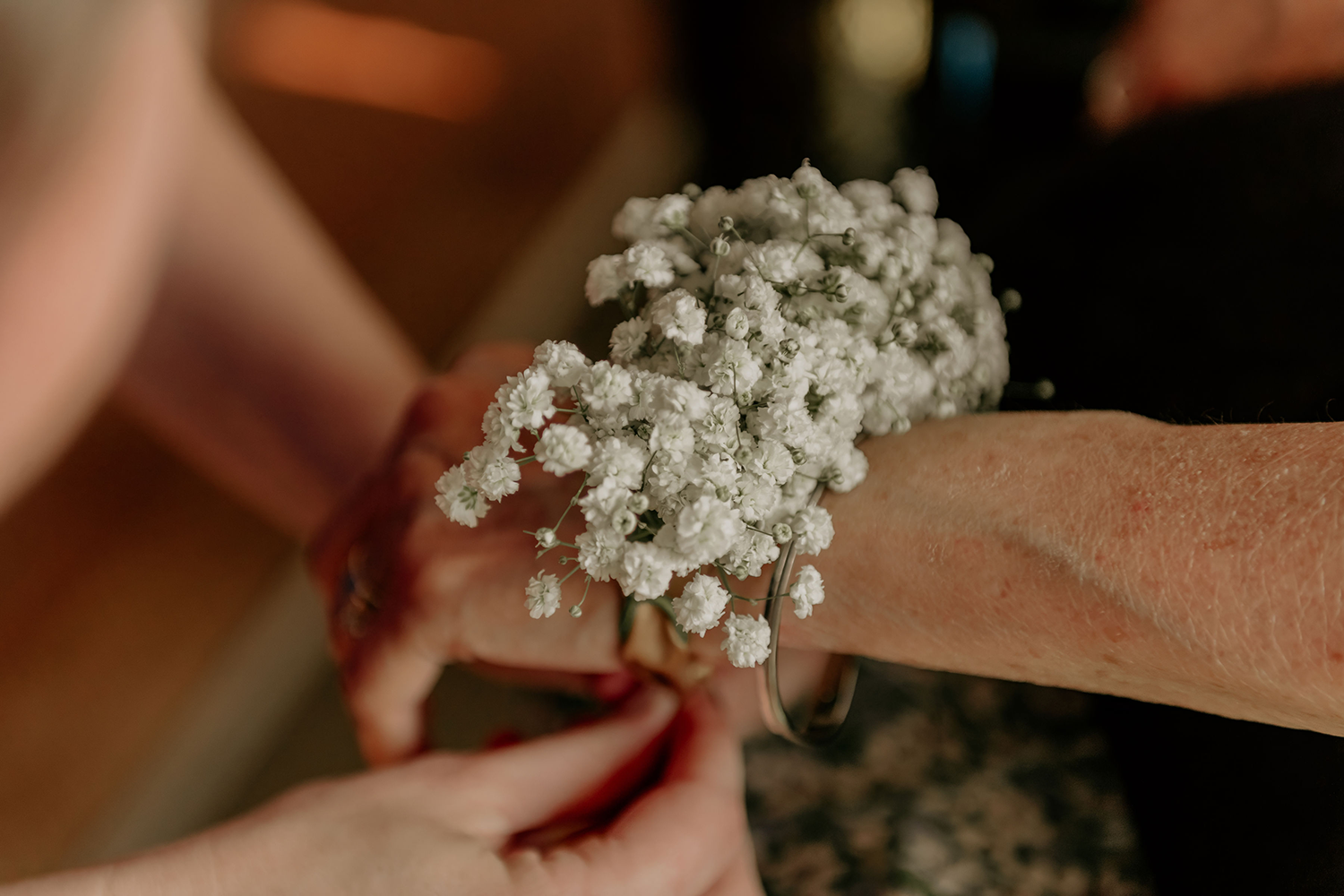 A woman is wearing a bracelet with baby 's breath on her wrist.