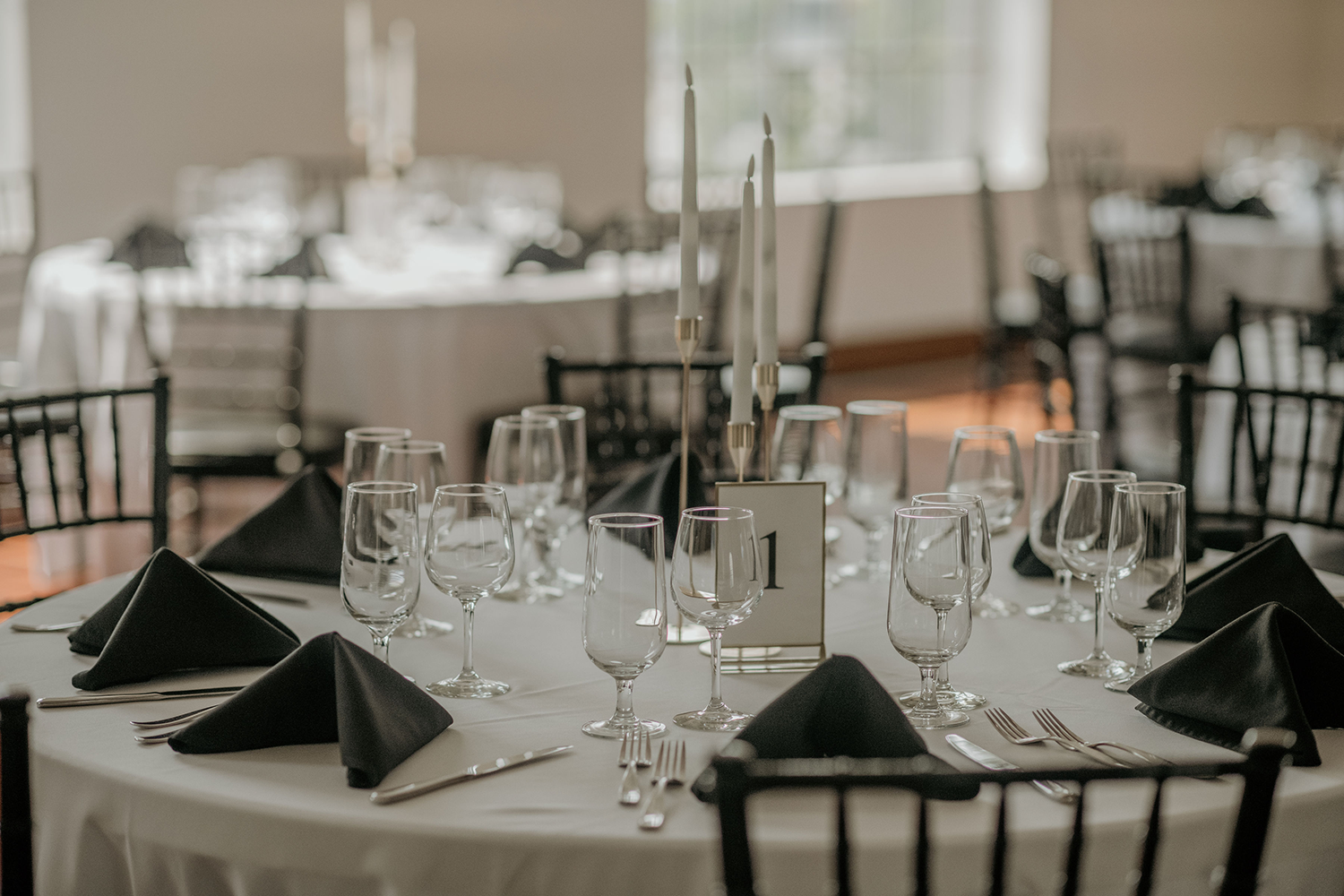 A table set for a wedding reception with black napkins and glasses.