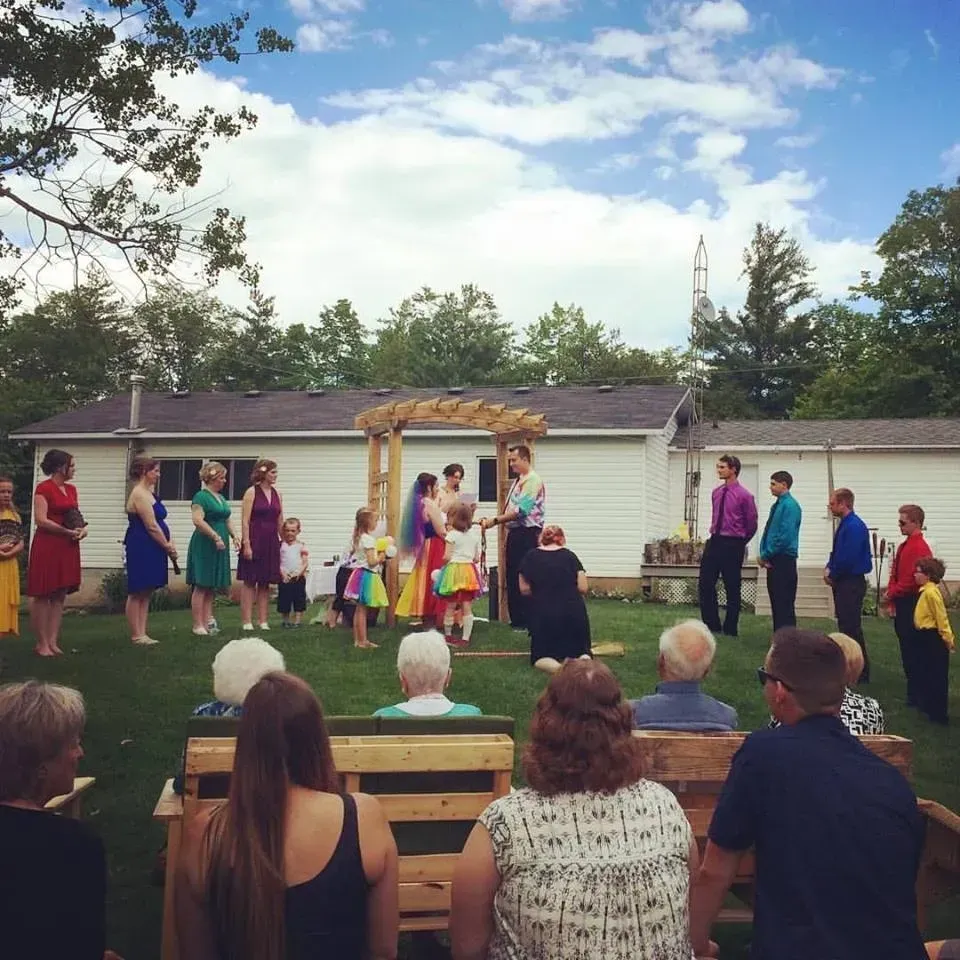A group of people are watching a wedding ceremony outside