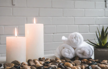 There are candles , towels and rocks on the table.