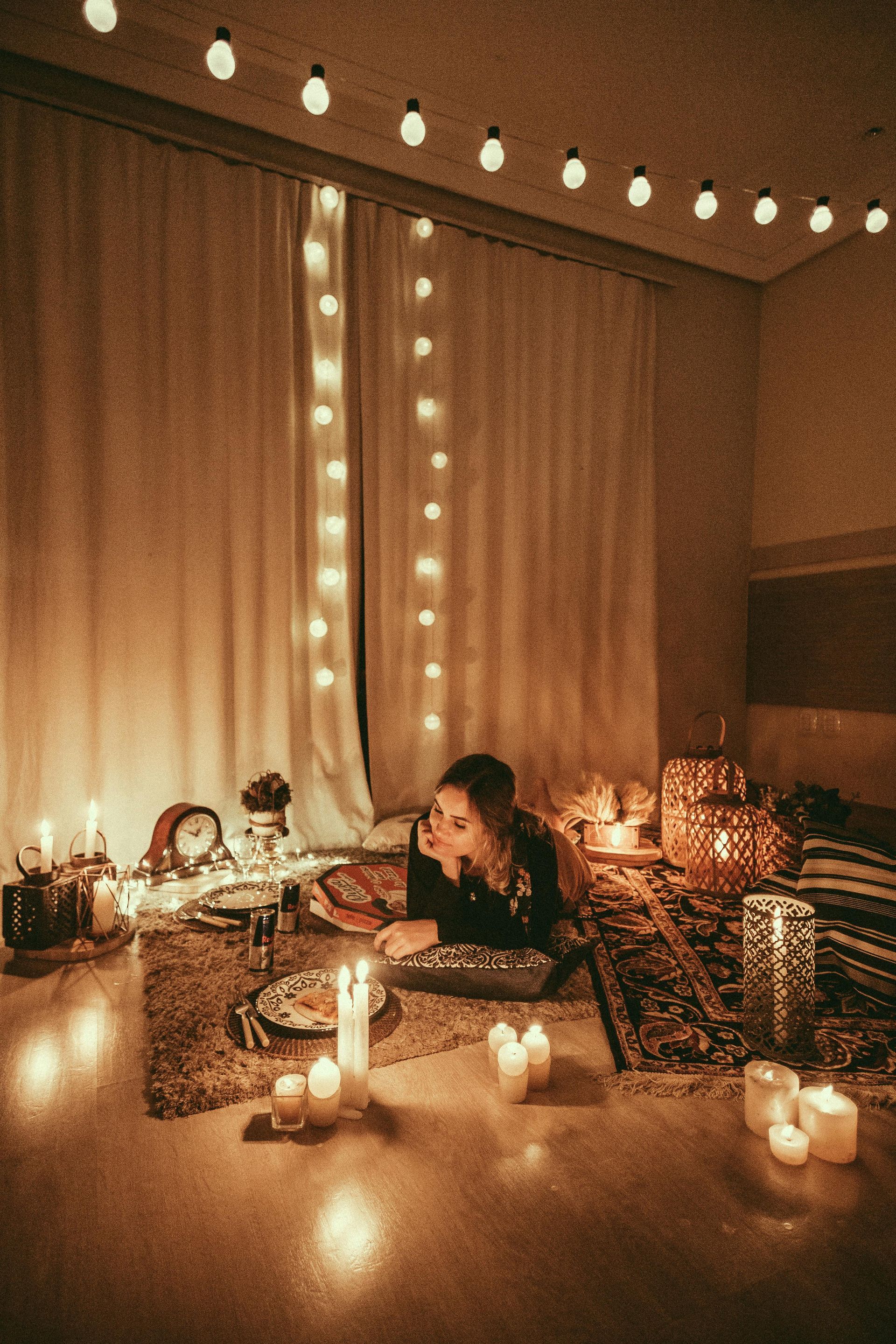 A woman is laying on the floor in a room with candles and lights.