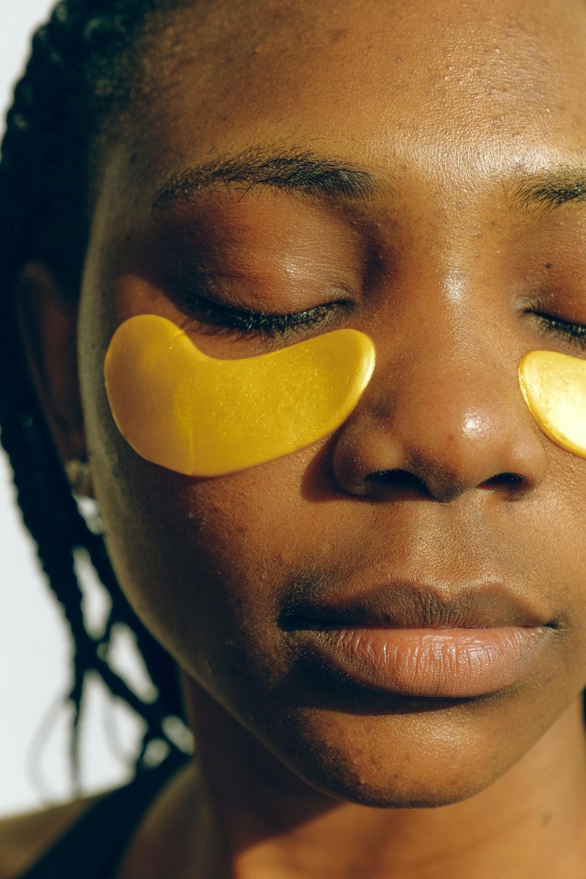 A close up of a woman 's face with yellow eye patches on her eyes.