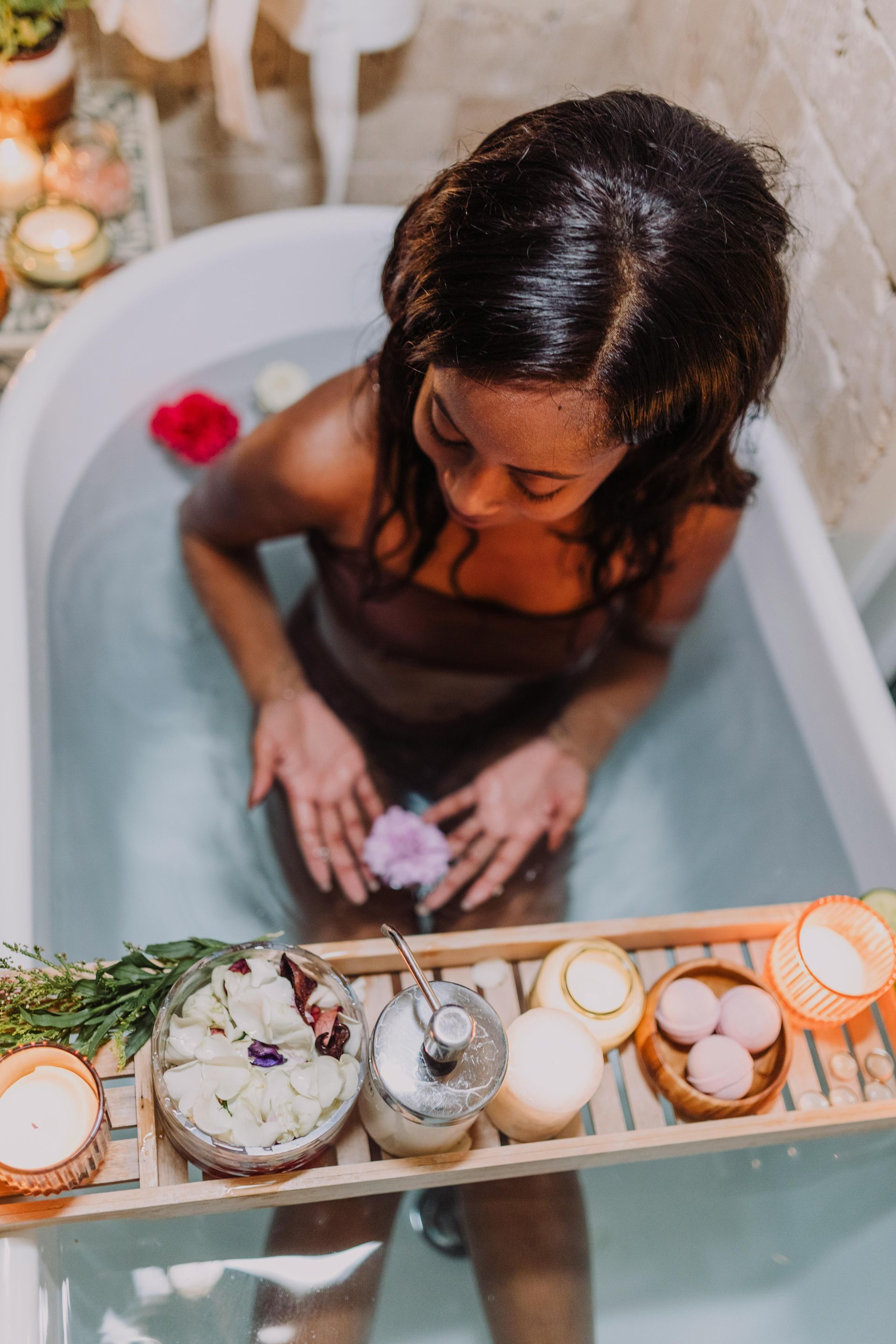A woman is sitting in a bathtub holding a flower.