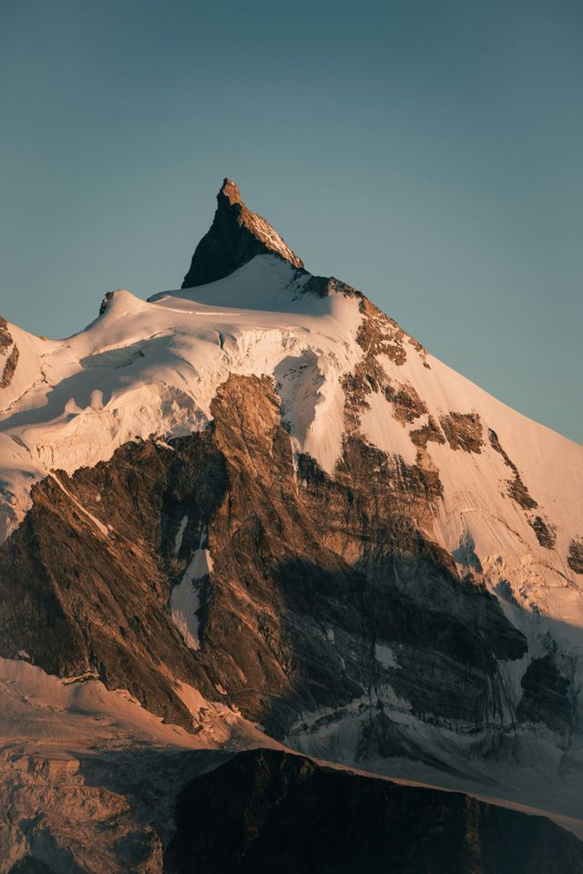 A mountain covered in snow and ice with a blue sky in the background.
