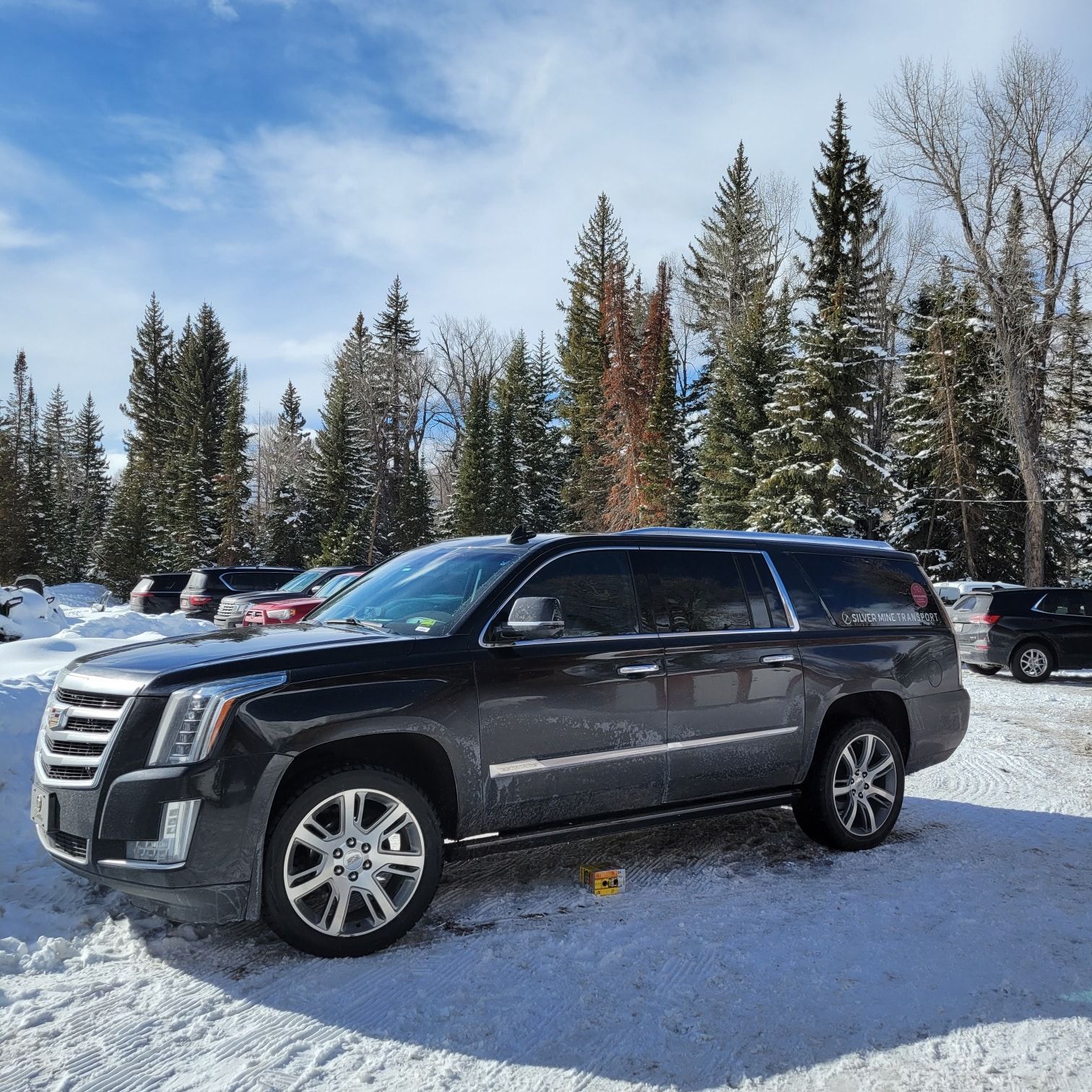 A black suv is parked in the snow in a parking lot