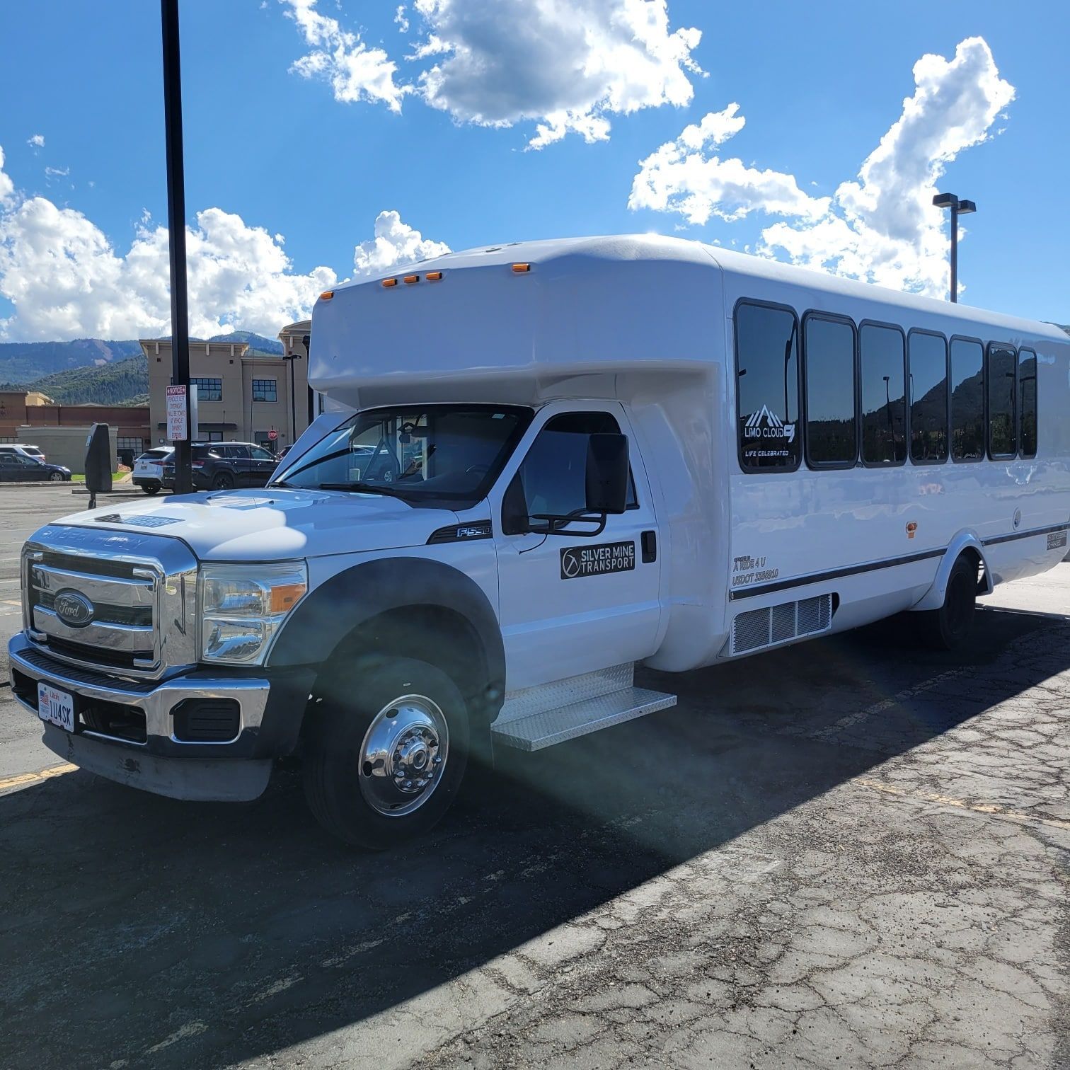 A white bus is parked in a parking lot on a sunny day