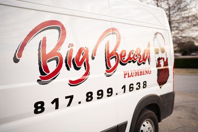 Copper and black pipes against a gray concrete wall, part of a building’s plumbing system.