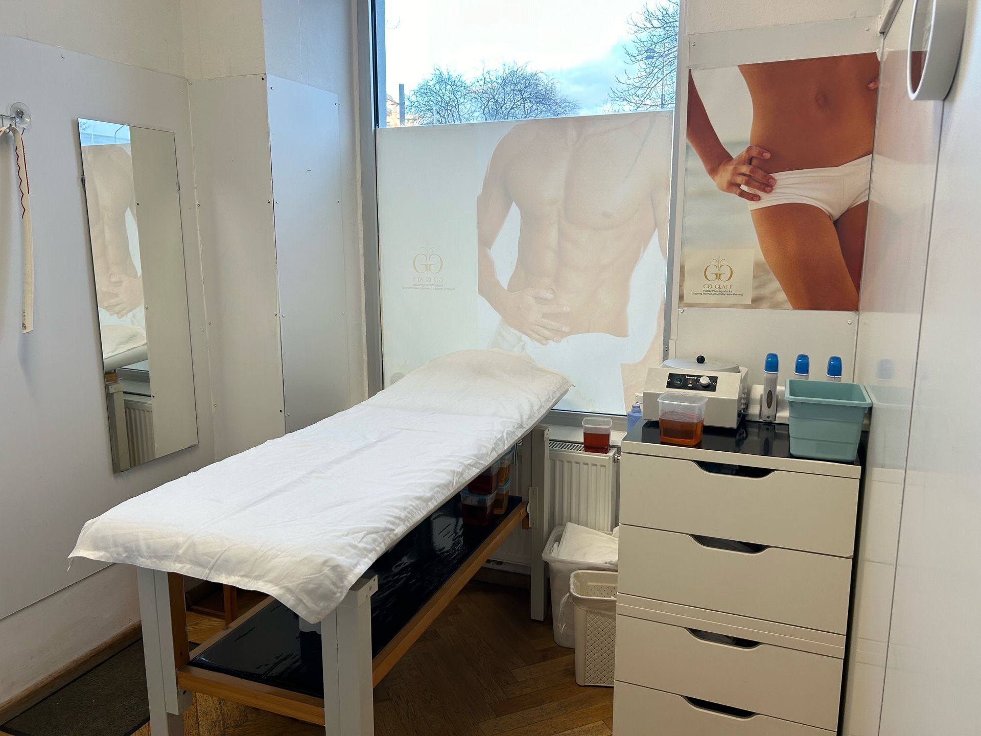 Ein Zimmer mit einem Bett, einer Kommode, einem Spiegel und einem Bild einer Frau an der Wand.