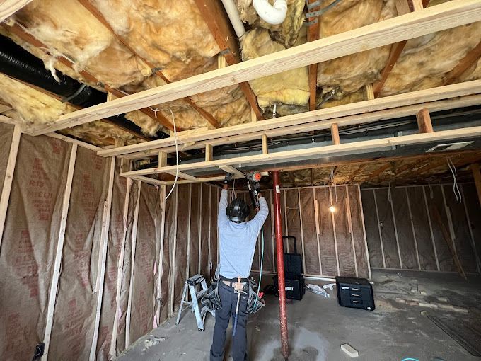 A man is working on the ceiling of a room under construction.