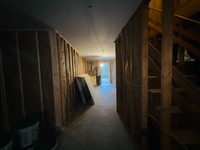 A hallway with wooden walls and stairs in a house under construction.