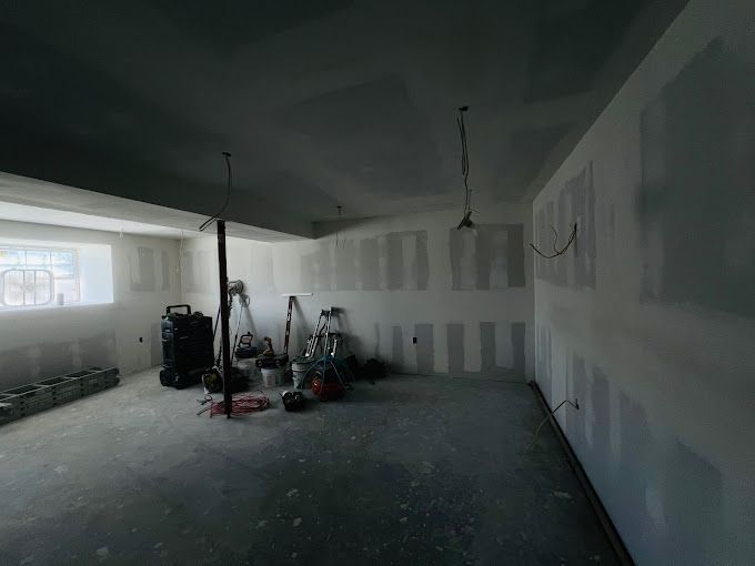 An empty room with a ladder and a vacuum cleaner in it.