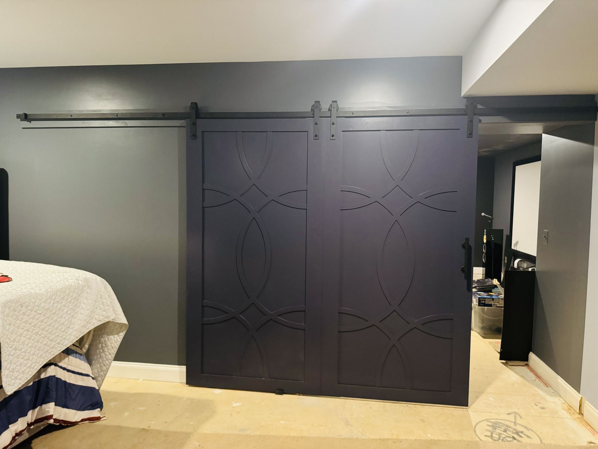 A bedroom with a sliding barn door and a bed