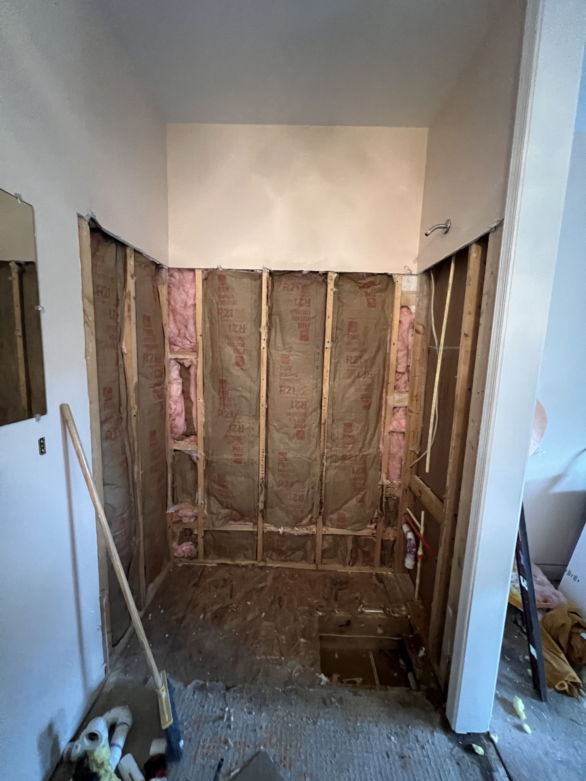 A room with a mirror and a broom in it is being remodeled.